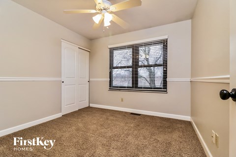 the living room is spacious and clean with carpet and a ceiling fan