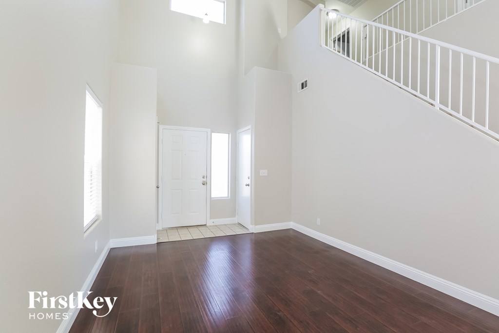 A spacious room with wooden floors and a staircase.