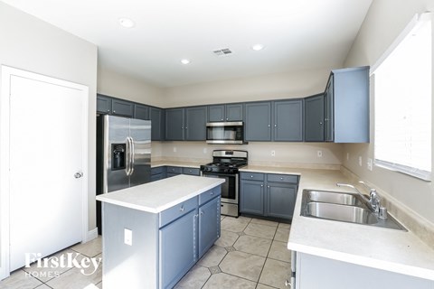 A kitchen with a white counter top and blue cabinets.