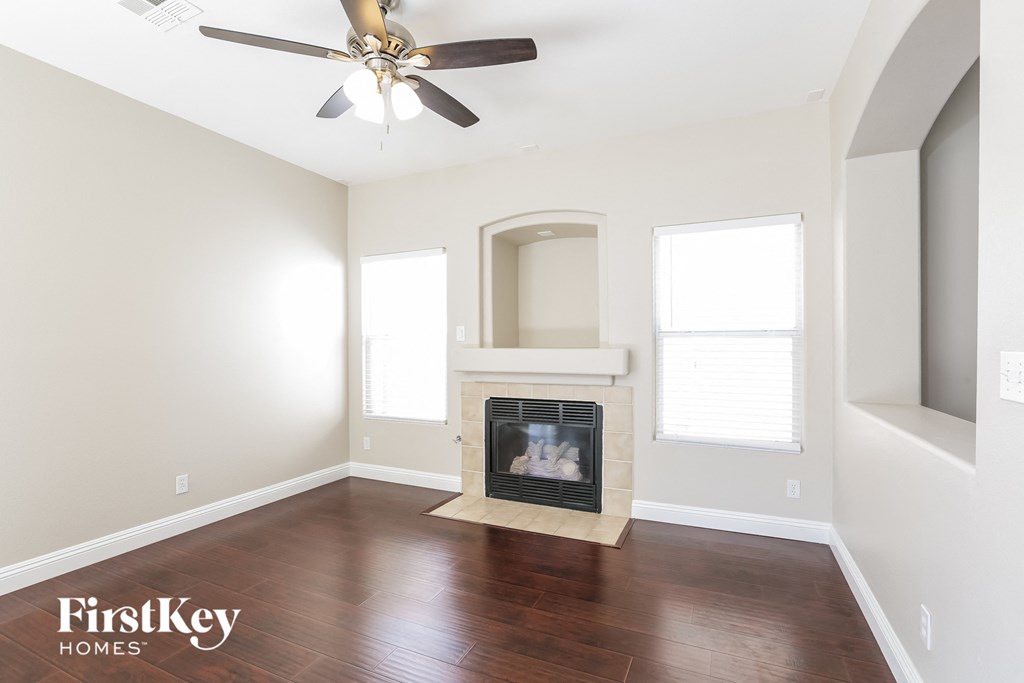 A living room with a fireplace and a ceiling fan.