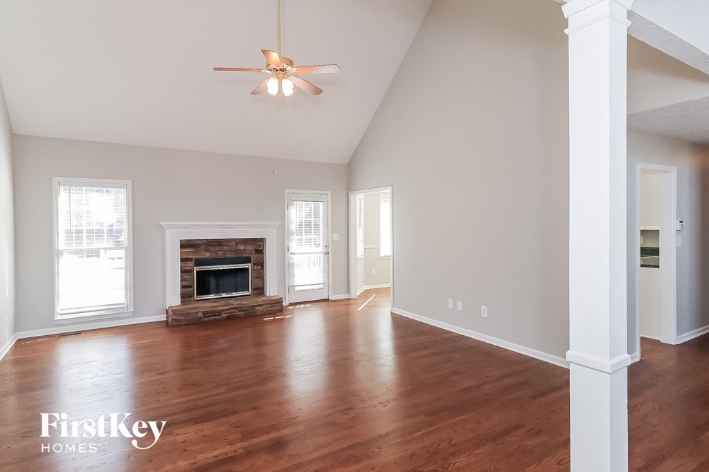 A spacious room with a fireplace and wooden floors.