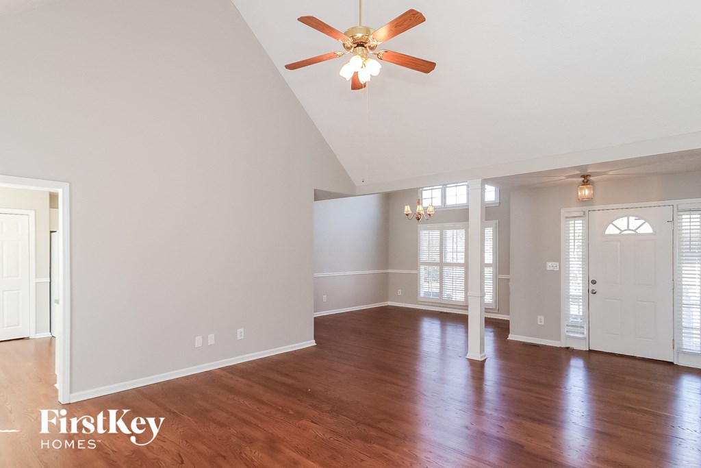 A spacious room with a ceiling fan and wooden floors.