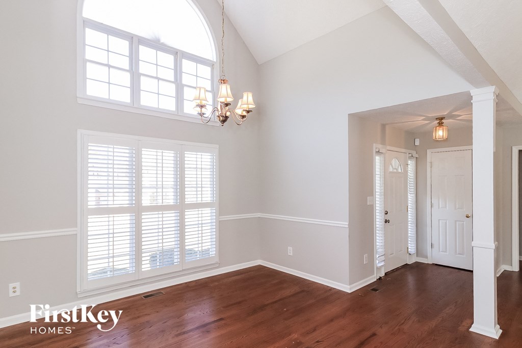 A room with wooden floors and a large arched window.