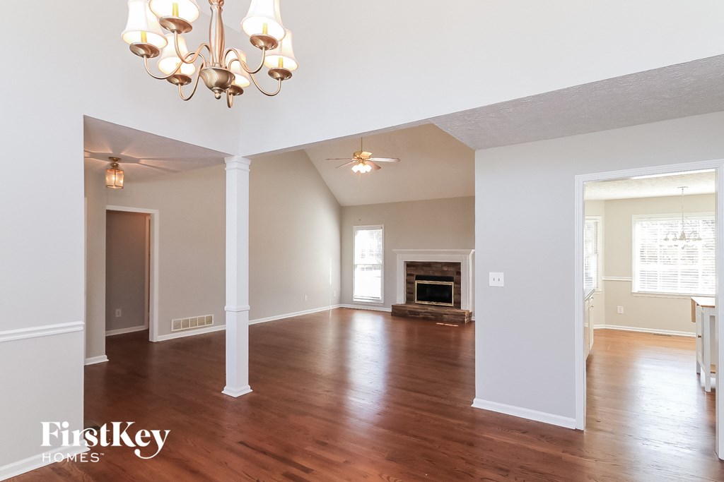 A large, empty room with a fireplace and a chandelier.