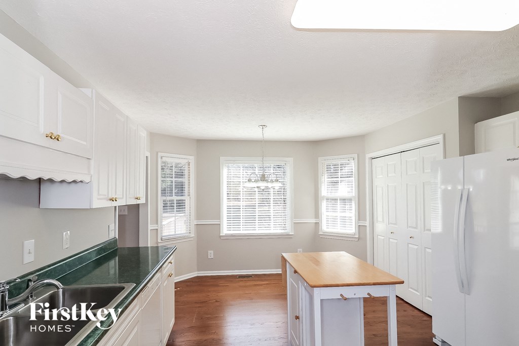 A kitchen with white cabinets and a green counter top.