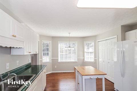 A kitchen with white cabinets and a green counter top.