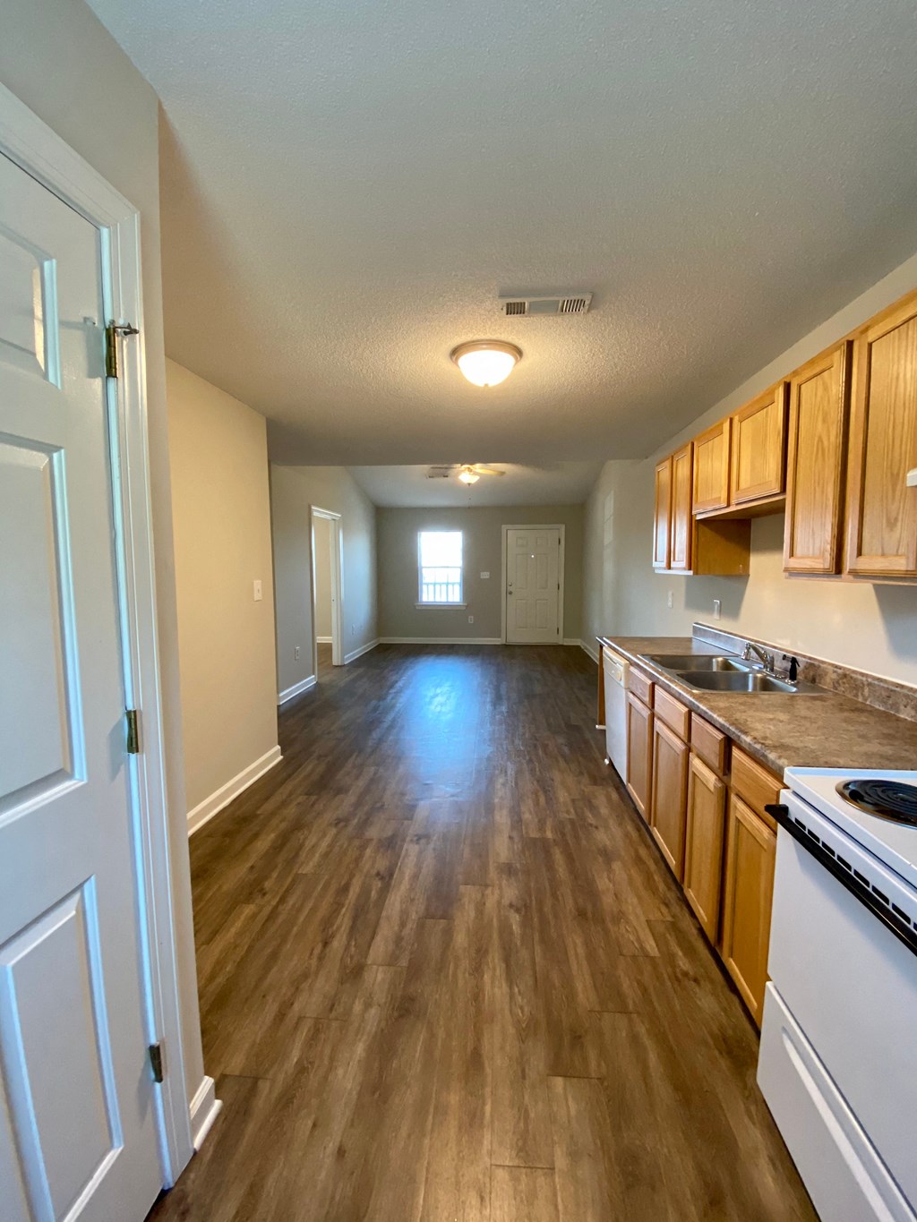 A long hallway with wood floors and white walls.