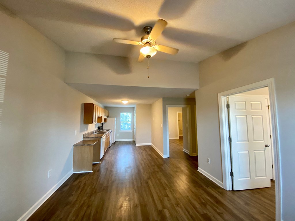 A spacious room with a ceiling fan and wooden floors.