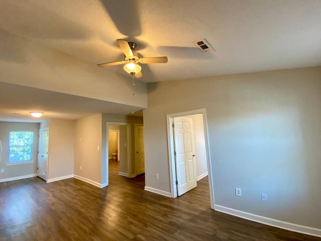 A room with a ceiling fan and wooden floors.