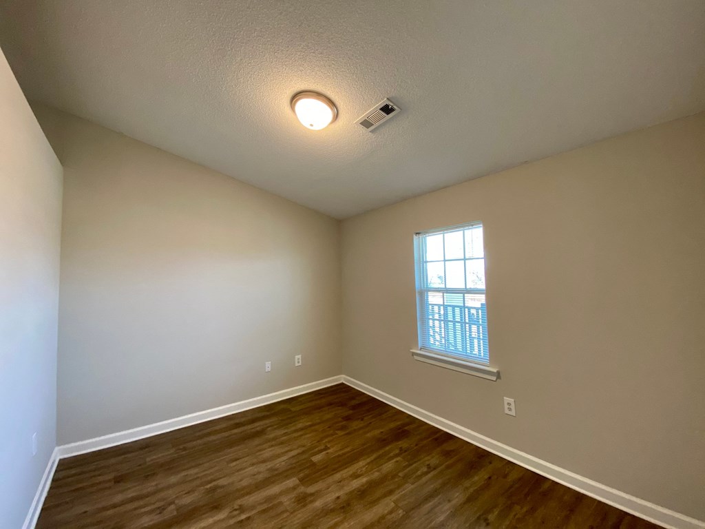 A room with a window and wooden flooring.