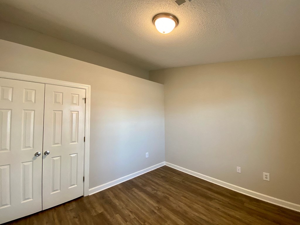 A room with a white door and wooden flooring.