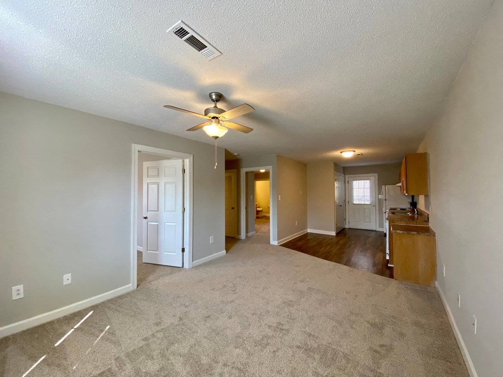 A spacious room with a ceiling fan and carpeted floor.