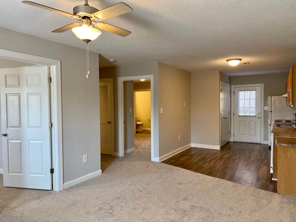 A room with a ceiling fan and carpeted floor.