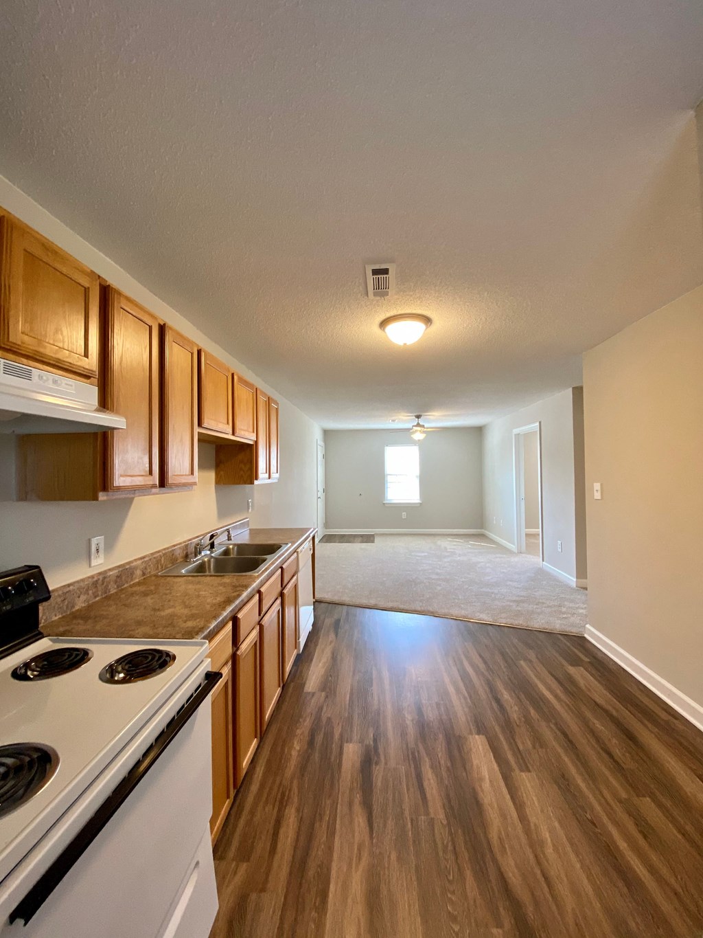A kitchen with wooden cabinets and a white stove top oven.