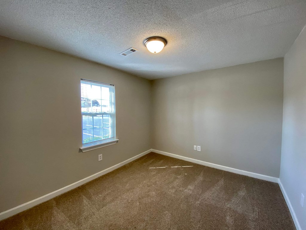 A room with a carpeted floor and a window.