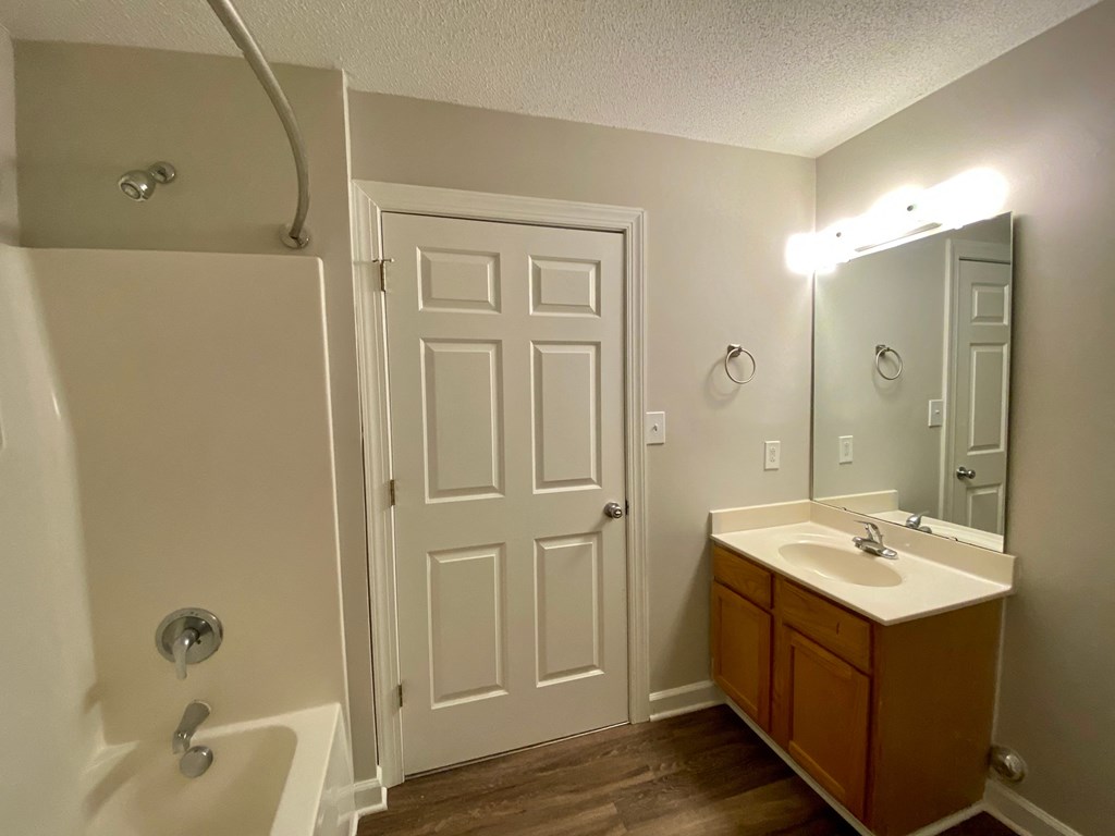 A bathroom with a white door, a sink, and a mirror.