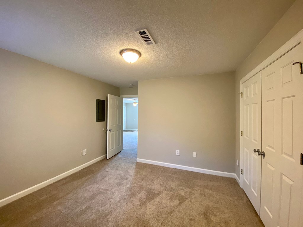 A room with a carpeted floor and two doors.