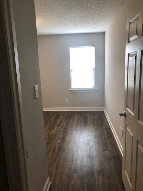 A hallway with a wooden floor and a window.