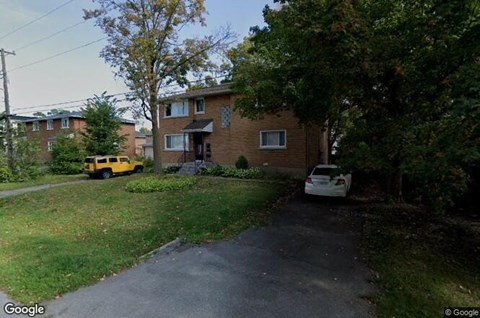 A white car is parked in front of a house.