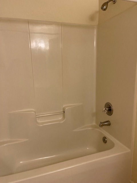 A white bathtub with a silver faucet and a shower head.