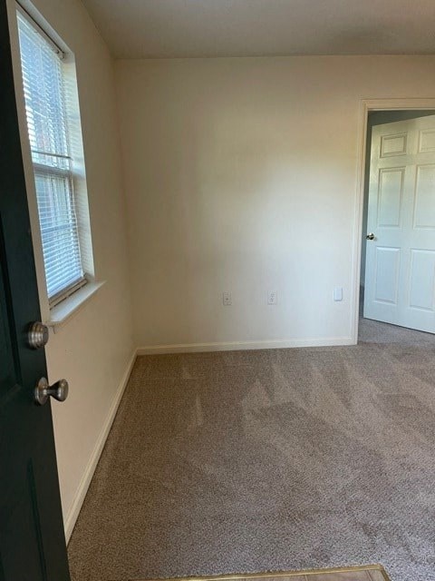 A room with a carpeted floor and a door.