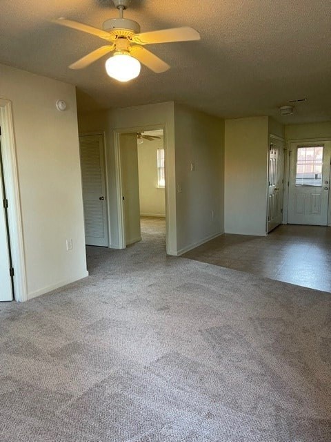 A room with a ceiling fan and carpeted floor.