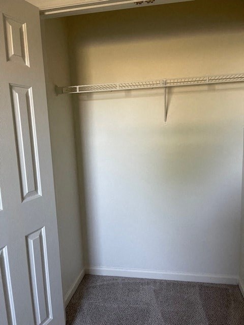 A white door is on the left of a white wall with a shelf on the right.