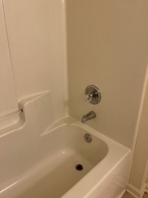 A white bathtub with a shower head and a faucet.