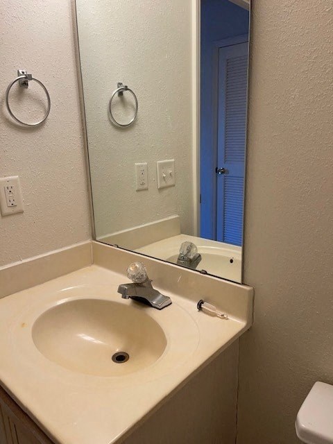 A bathroom with a sink, mirror, and toilet.