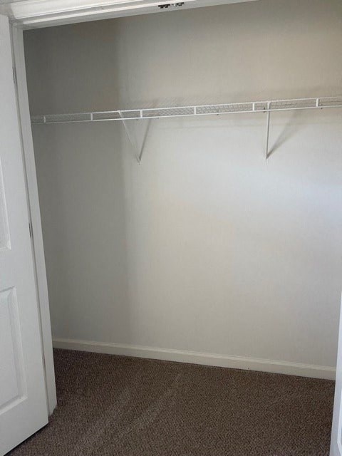 A white door is on the left side of a room with a white wall and a white closet rod.