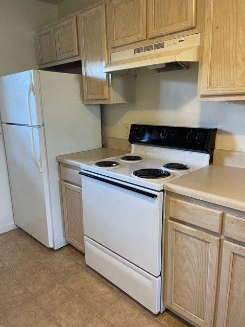 A white stove and refrigerator in a kitchen.