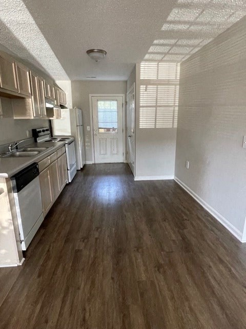 A kitchen with white appliances and wooden floors.