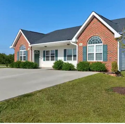 A red brick house with green shutters and a white garage door.