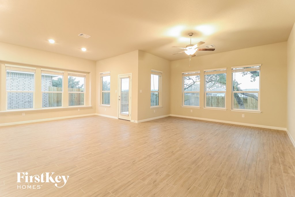 an empty living room with a ceiling fan and windows