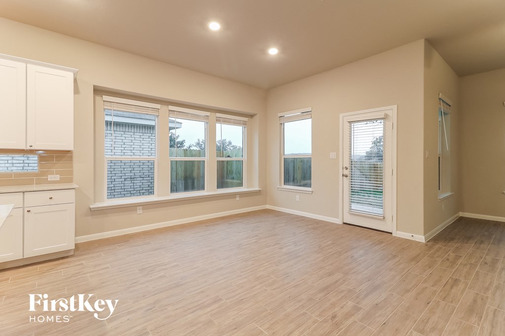 an empty living room with windows and a kitchen