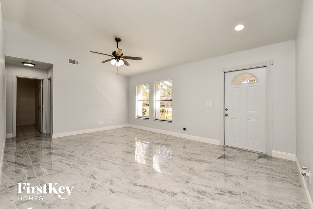 an empty living room with a white door and a ceiling fan