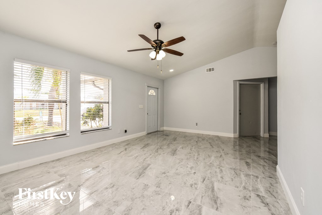 an empty living room with white walls and a ceiling fan