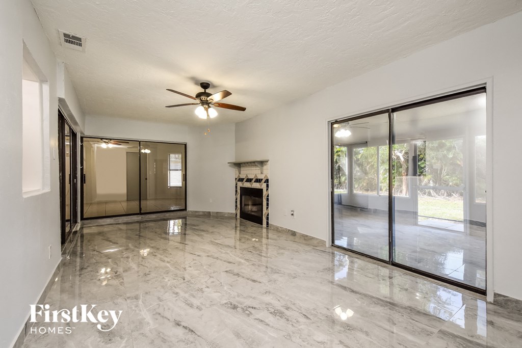an empty living room with a ceiling fan and sliding glass doors