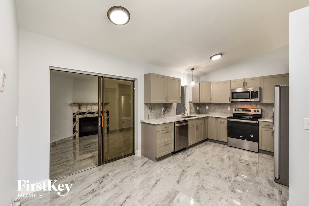 a large kitchen with stainless steel appliances and marble flooring