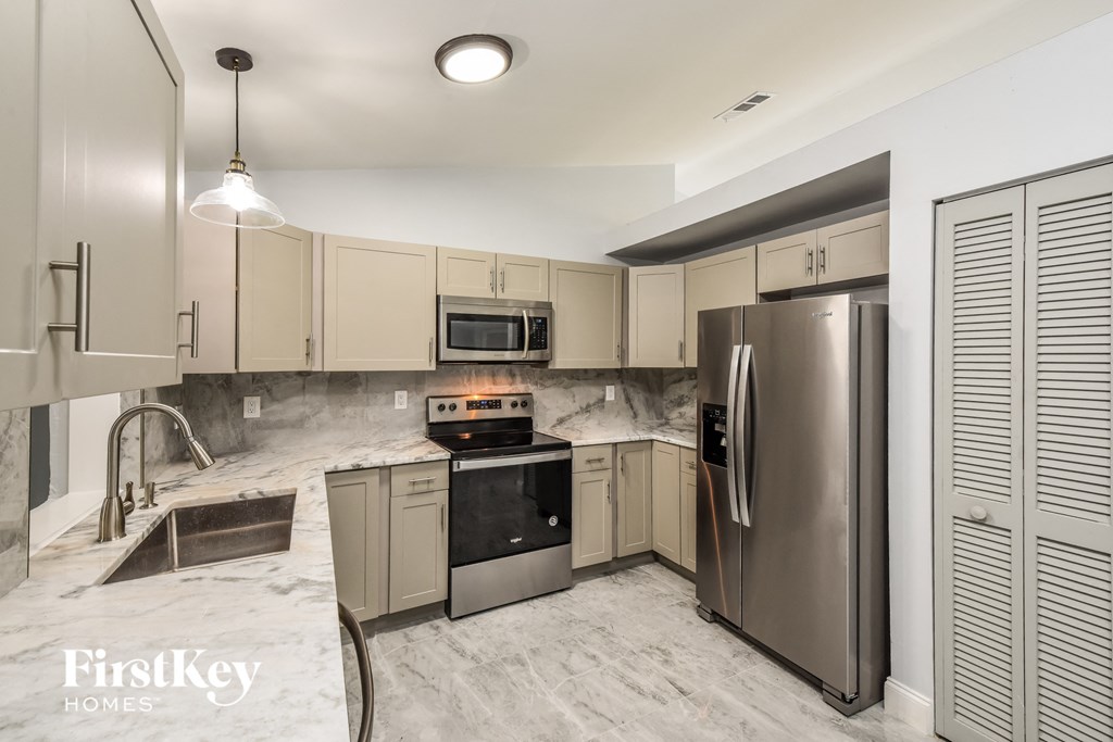 a white kitchen with stainless steel appliances and marble counter tops