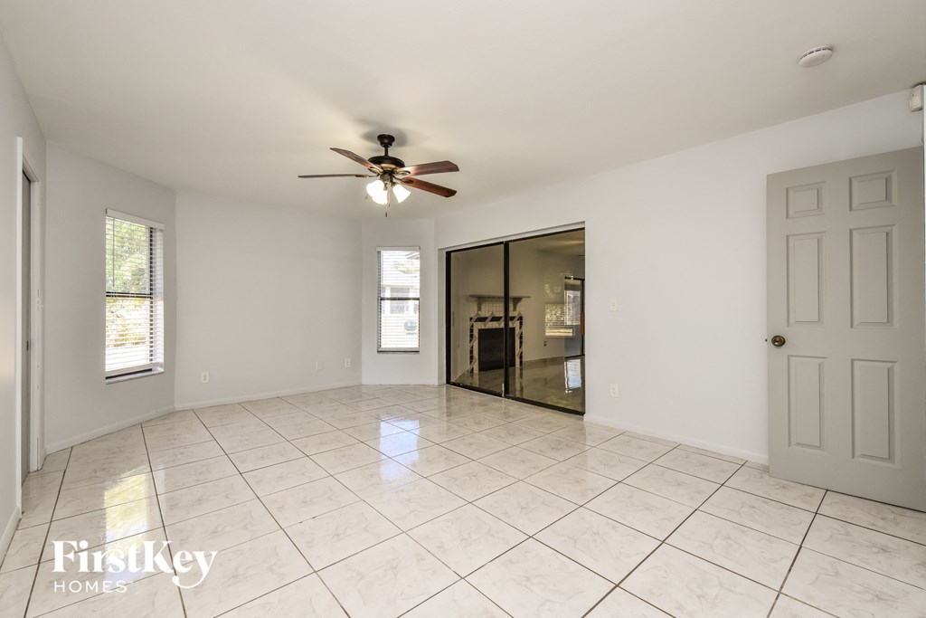 an empty living room with a ceiling fan and tiled floor