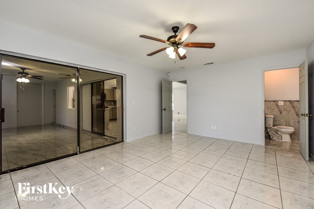 a clean and empty living room with a large mirror and a ceiling fan