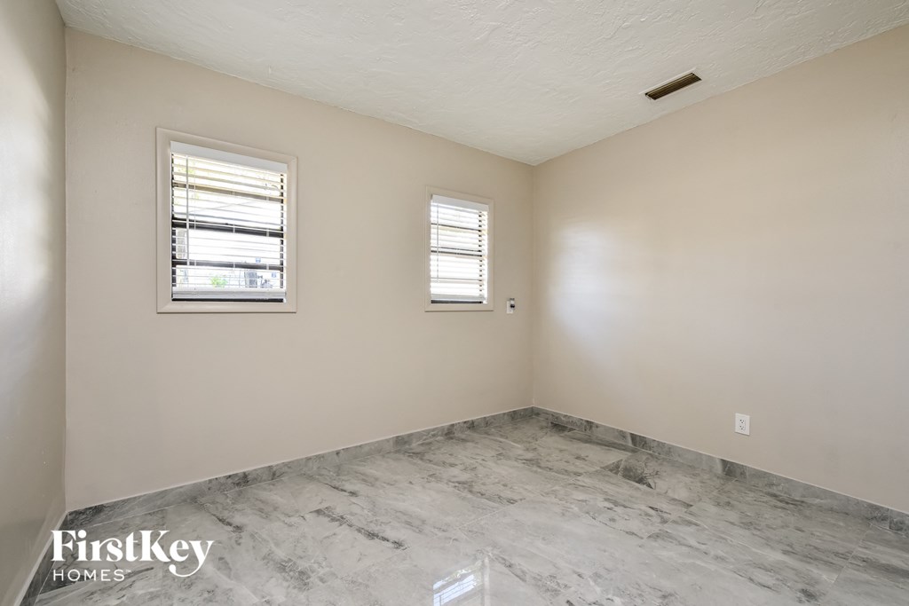the living room of an empty house with a marble floor and a window