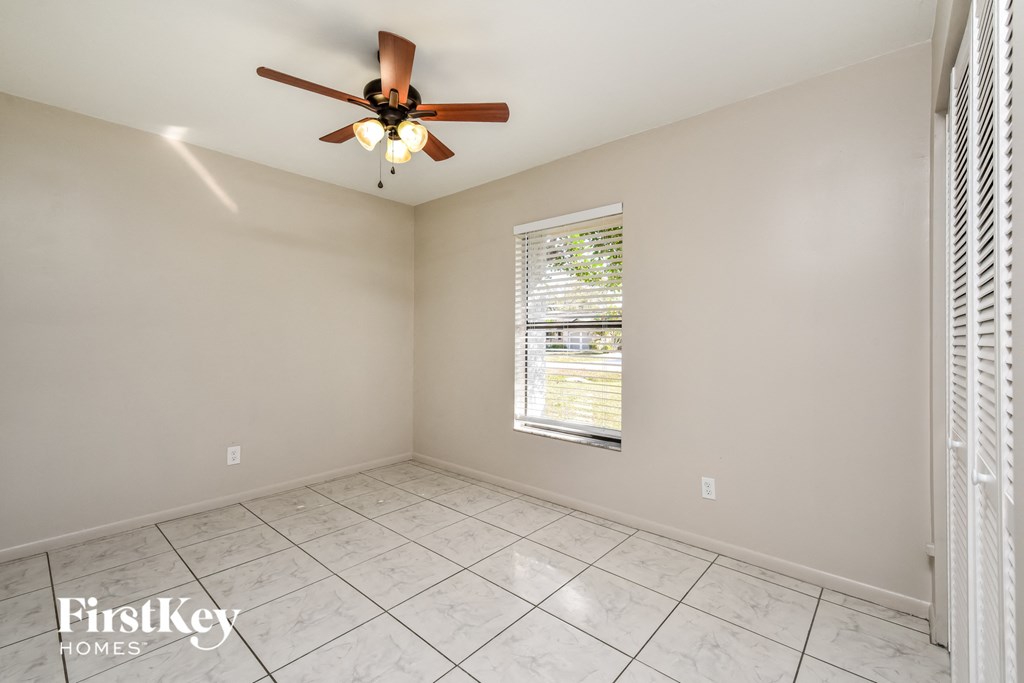 an empty living room with a ceiling fan and a window