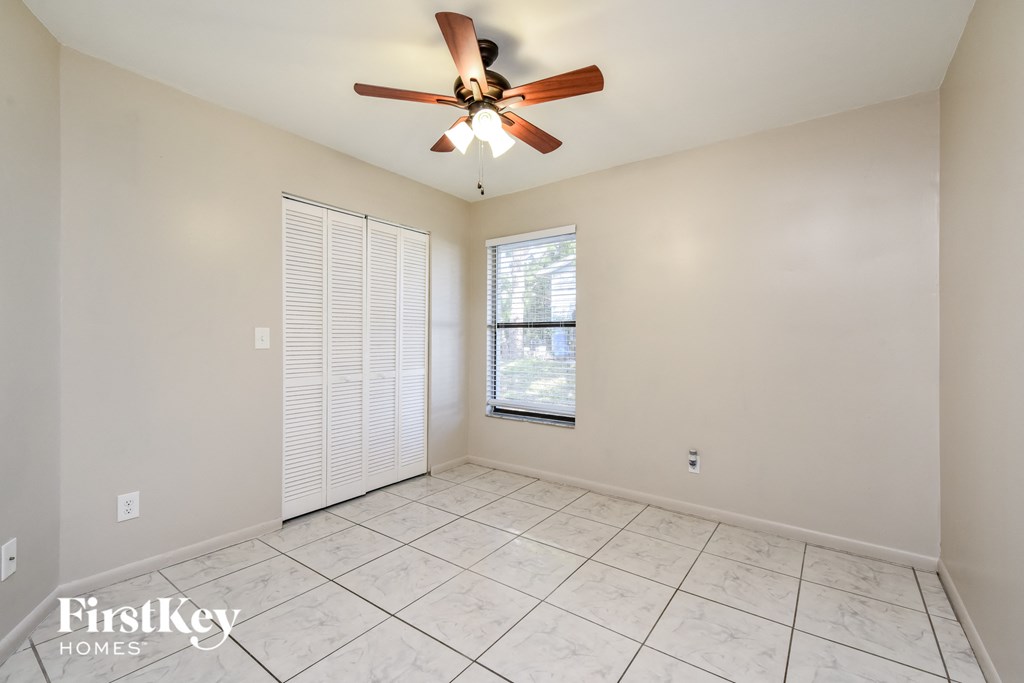 an empty living room with a ceiling fan and a window