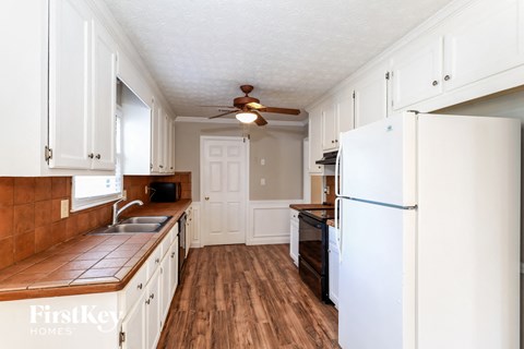 A kitchen with a white refrigerator and wooden floors.