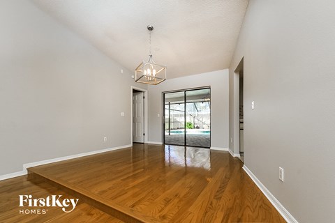 a spacious living room with hardwood flooring and a door to the pool