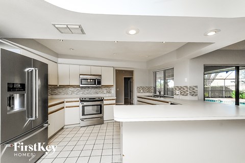 a white kitchen with stainless steel appliances and a white counter top