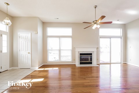 A spacious living room with a fireplace and a ceiling fan.