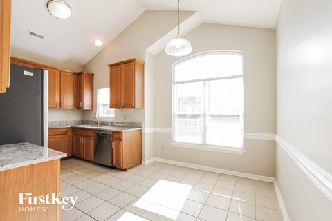A kitchen with wooden cabinets and a black fridge.